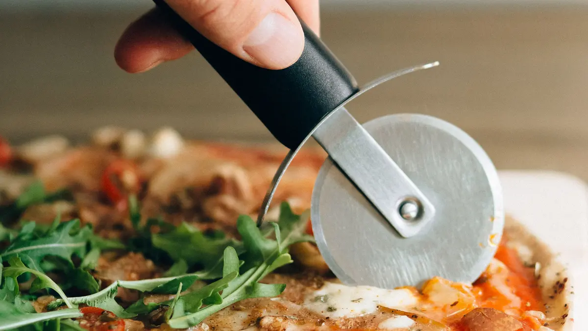 Pizza die met een roller-pizzasnijder wordt gesneden