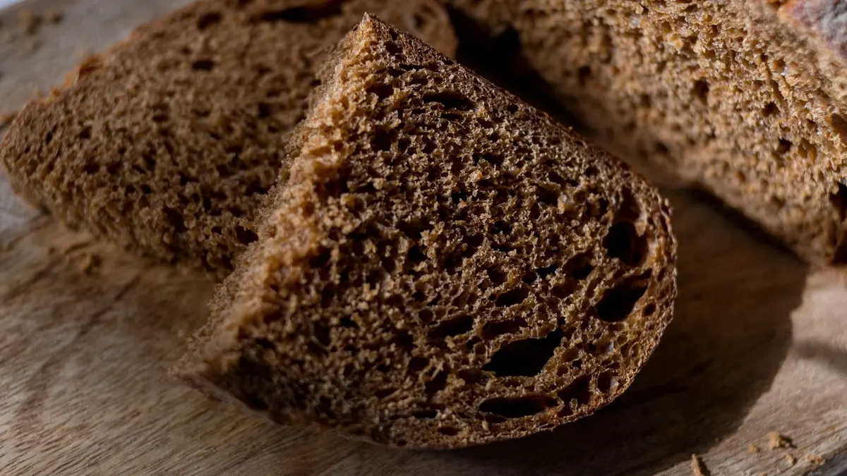 Aangesneden bruin volkoren brood met zichtbare kruim op een houten snijplank
